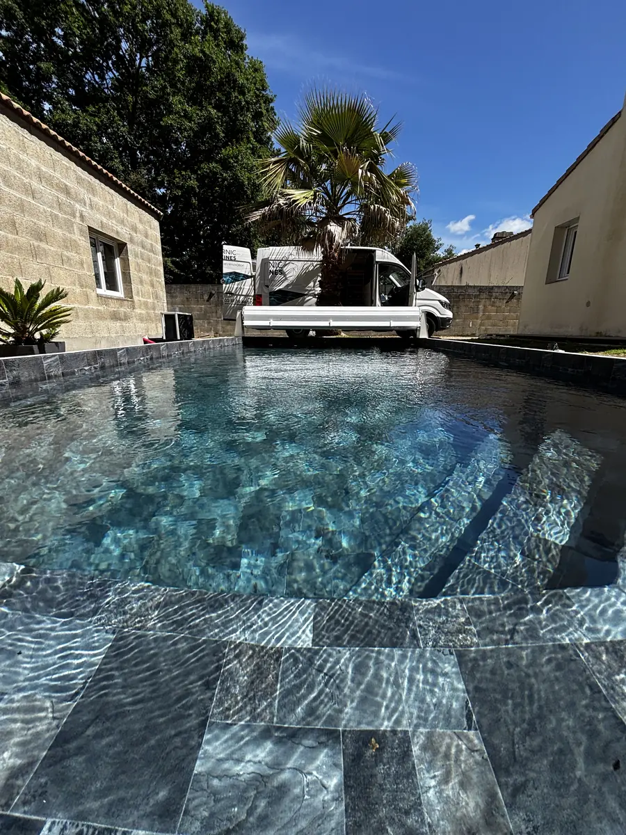 Le même bassin aspect carrelage anthracite rempli d'eau, devant le camion Pornic Piscines